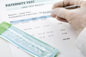 Laboratory professional in gloves reviewing paternity test results document showing 99.2% probability of paternity from AABB accredited DNA testing facility