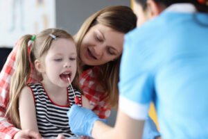 Healthcare professional collecting gentle cheek swab DNA sample from child with mother present showing family-friendly paternity testing process in Nashville